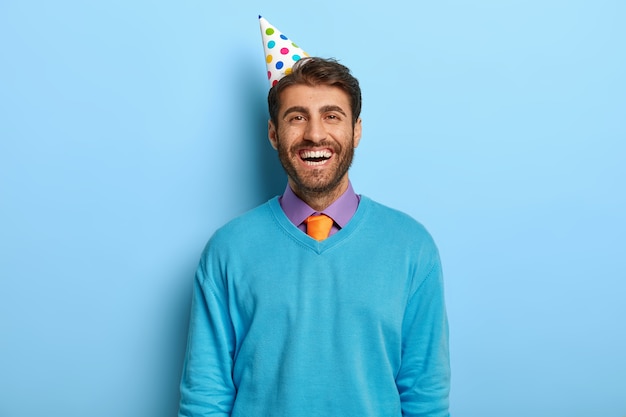 Foto grátis cara alegre e otimista com chapéu de aniversário posando de suéter azul