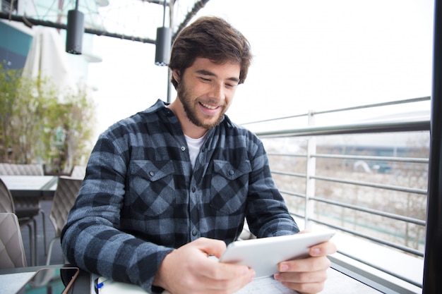 Foto grátis cara alegre, usando o gadget para conversar