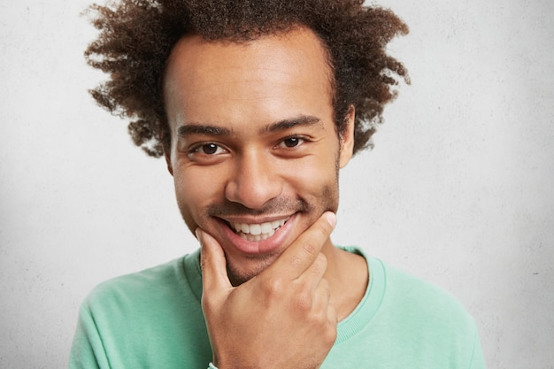 Cara bonito despreocupado com expressão alegre, sorri amplamente, demonstra dentes brancos e uniformes