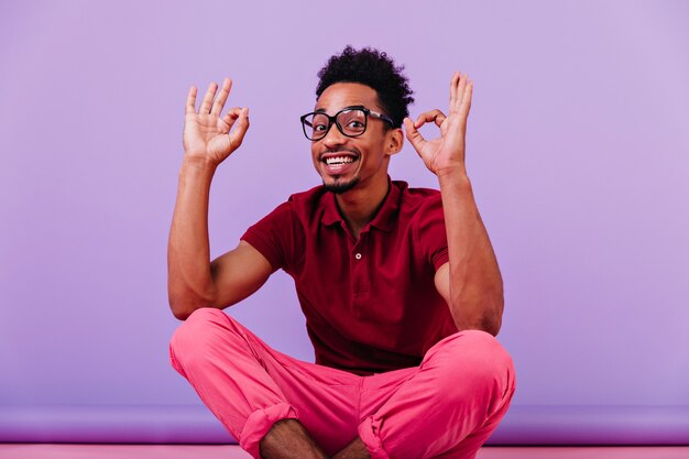 Cara bonito e inteligente fazendo caretas engraçadas. Rindo homem negro de bom humor, posando de óculos.