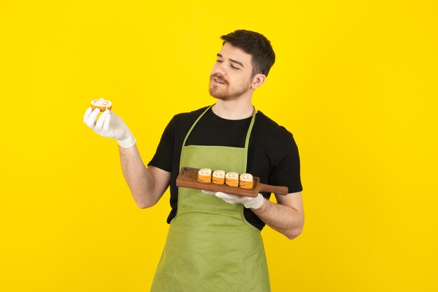 Cara bonito sorridente, olhando para o rolo de bolo em um amarelo.