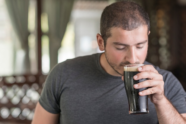 Cara cheirando cerveja no pub