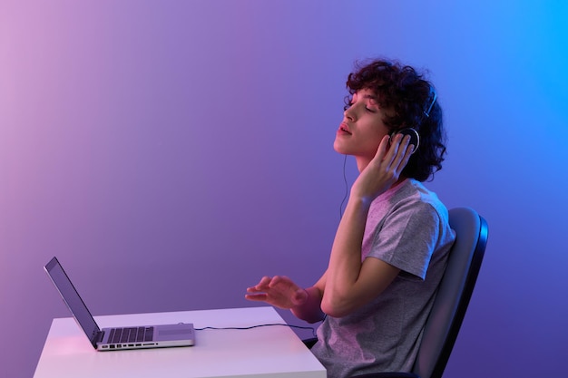 Cara ciberespaço brincando com fones de ouvido na frente de um fundo violeta de laptop