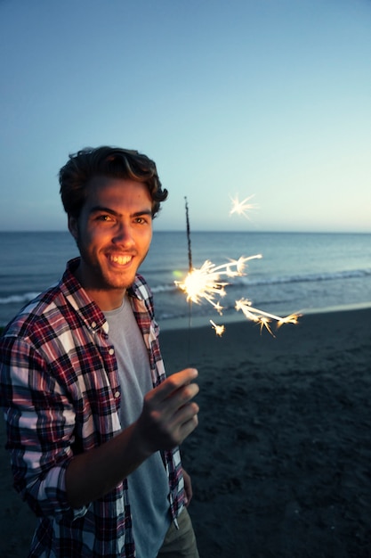 Cara com sparkler na praia