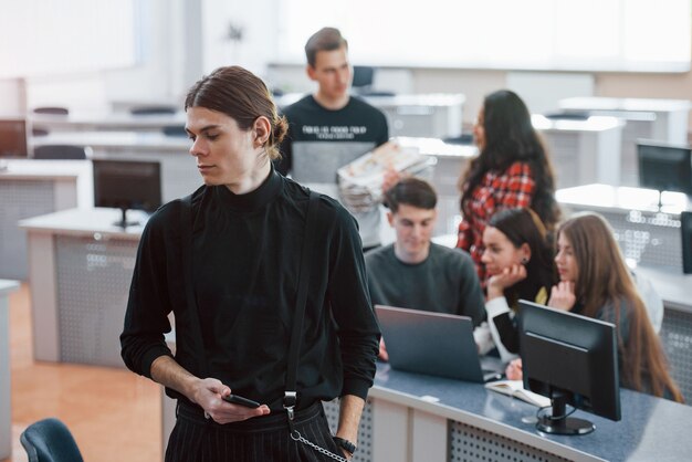 Cara de cabelos compridos. Grupo de jovens com roupas casuais, trabalhando em um escritório moderno