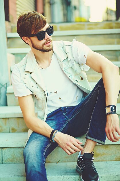 Cara de homem bonito hipster sorridente engraçado em pano elegante de verão na rua em óculos de sol