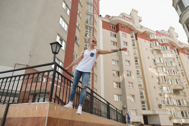 Cara de homem loiro bonito hipster em roupas de verão elegante na rua