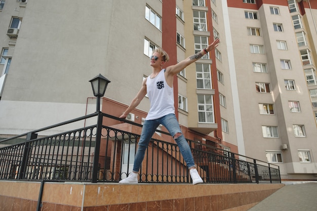 Cara de homem loiro bonito hipster em roupas de verão elegante na rua