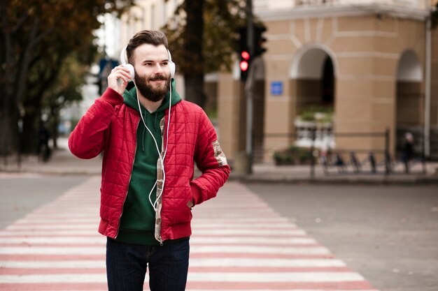 Cara de tiro médio com fones de ouvido atravessando a rua