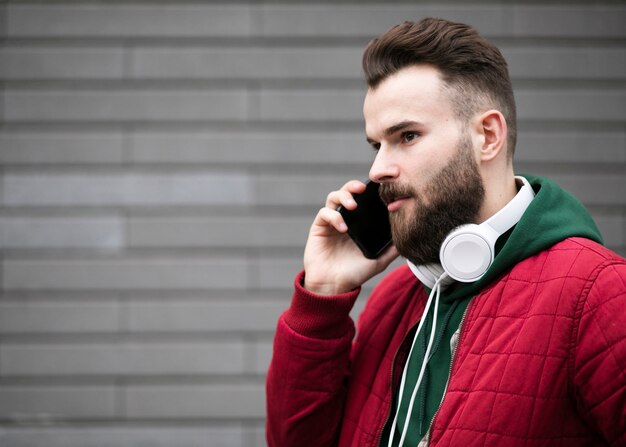 Cara de tiro médio com fones de ouvido falando ao telefone