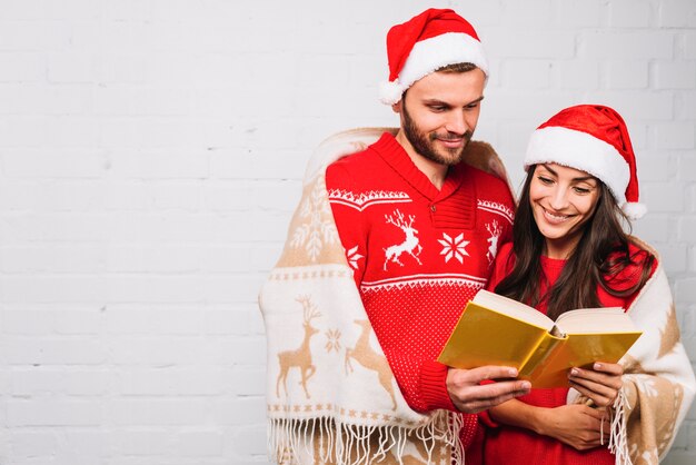 Cara e mulher em chapéus de festa, lendo o livro