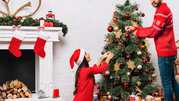 Cara e senhora vestindo árvore de Natal