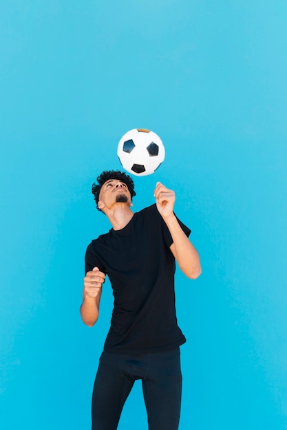 Cara étnica com cabelo encaracolado, brincando com futebol