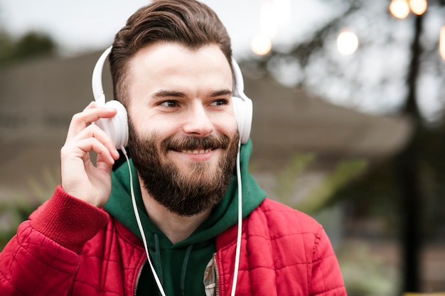 Cara feliz de close-up com fones de ouvido e jaqueta vermelha