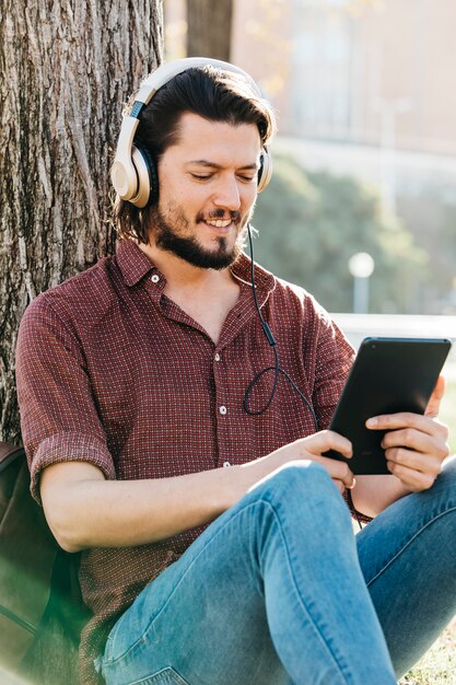 Cara feliz usando um telefone inteligente para ouvir música com fones de ouvido