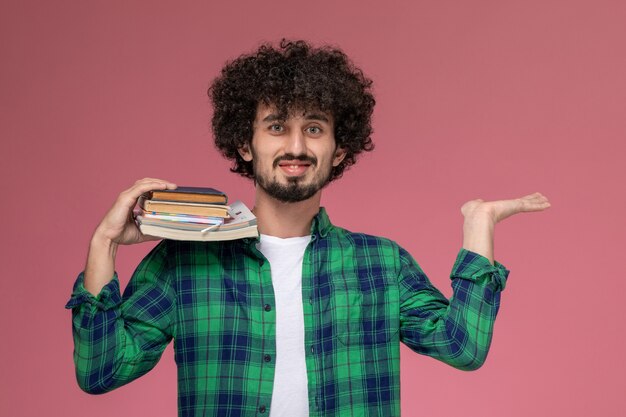 Cara jovem colocando seu caderno no ombro e mostra a mão vazia