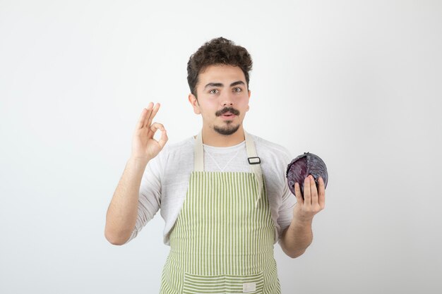 Cara jovem segurando repolho fresco e gesticulando OK.