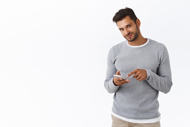 Cara mostrando algo na tela do celular homem barbudo hispânico atrevido apontando a tela do smartphone e câmera sorridente satisfeito impressionado com o bom colega de trabalho do projeto enviado via mensagens