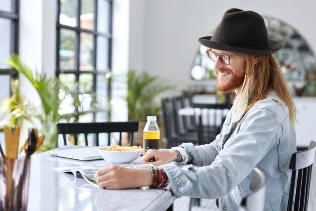 Cara na moda e hipster vestido com um chapéu preto estiloso e uma camisa jeans