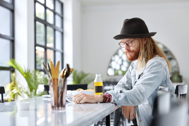 Cara na moda e hipster vestido com um chapéu preto estiloso e uma camisa jeans