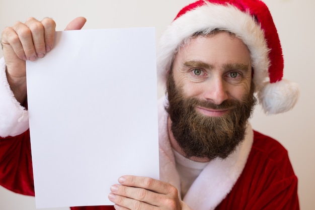 Cara sorridente, vestindo traje de papai noel e mostrando a folha de papel em branco