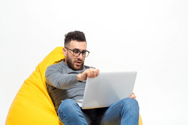 Foto grátis cara surpreso enquanto está sentado na cadeira de pufe amarelo