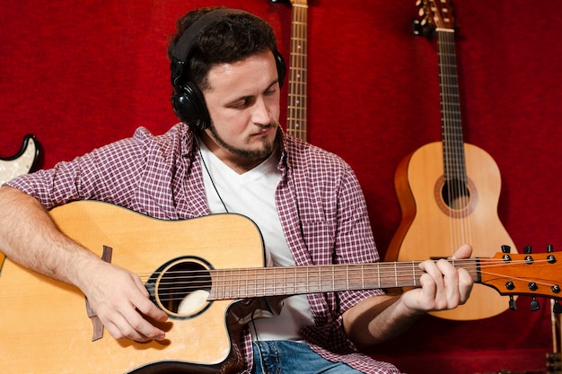 Cara tocando violão no estúdio