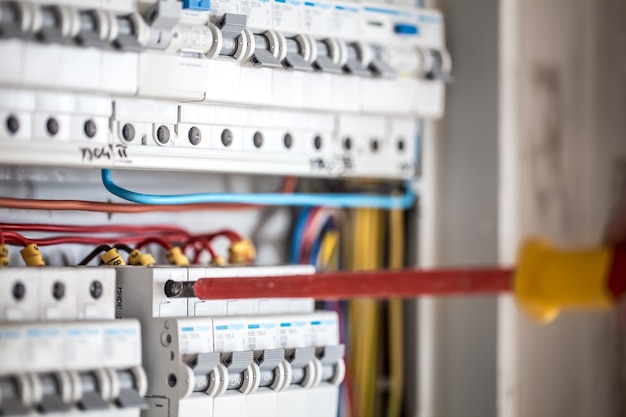 Foto grátis cara, um eletricista trabalhando em uma central telefônica com fusíveis. instalação e conexão de equipamentos elétricos. fechar-se.