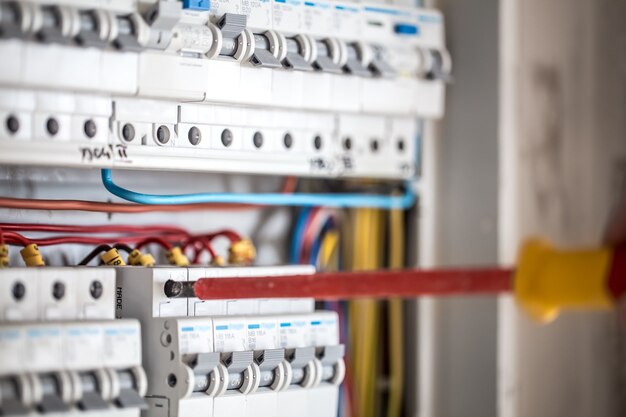 Cara, um eletricista trabalhando em uma central telefônica com fusíveis. Instalação e conexão de equipamentos elétricos. Fechar-se.