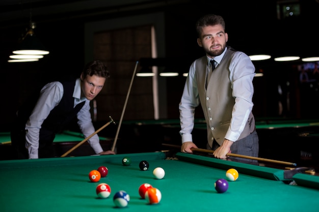 Foto grátis caras de tiro médio no clube de bilhar com coletes