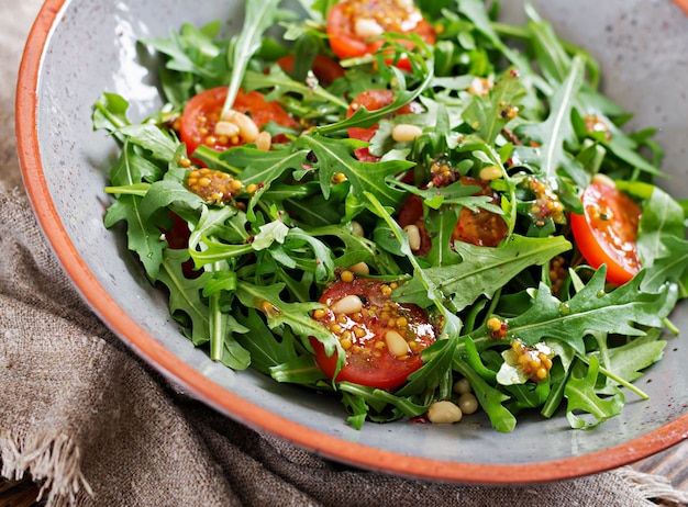 Cardápio dietético. Cozinha vegana. Salada saudável com rúcula, tomate e pinhões.