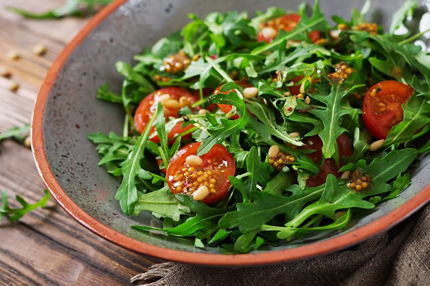 Cardápio dietético. Cozinha vegana. Salada saudável com rúcula, tomate e pinhões.