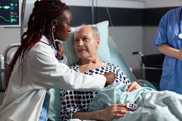 Cardiologista afro-americano examinando o coração do paciente sênior