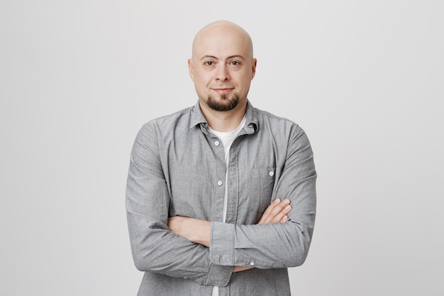 Careca autoconfiante com barba, braços cruzados, peito e sorriso