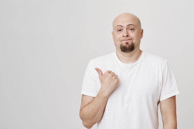 Careca indiferente e barbudo apontando o dedo para a esquerda