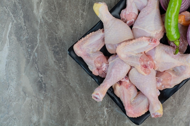 Carne de frango cru com pimentão e cebola na chapa escura. Foto de alta qualidade