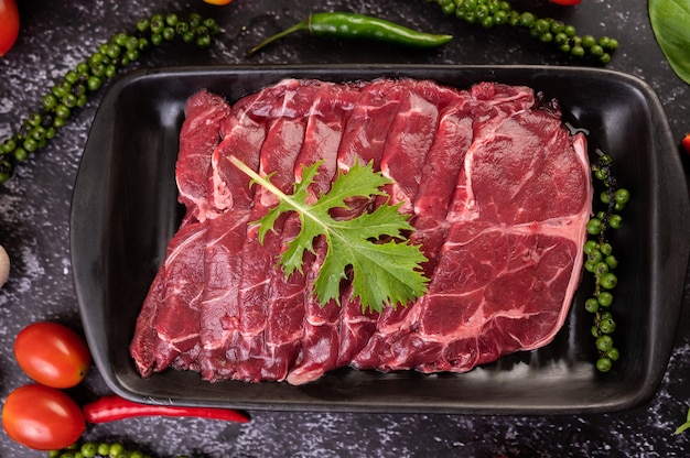 Carne de porco crua fatiada usada para cozinhar com sementes de pimentão, tomate, manjericão e pimenta fresca.