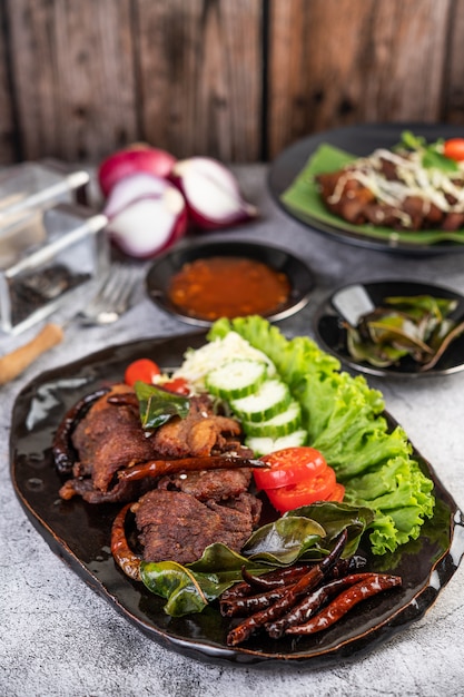 Carne de porco frita coberta com gergelim, colocado em um prato preto.