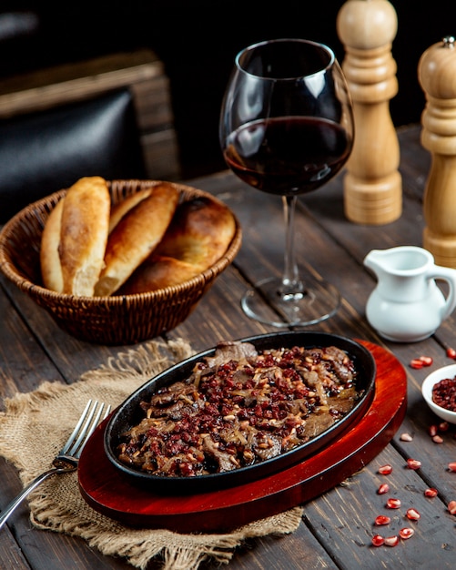 Foto grátis carne frita com romã e copo de vinho tinto