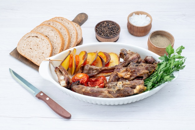 carne frita com verduras e ameixas assadas dentro do prato com pães na mesa de luz, refeição refeição prato de carne jantar vegetais