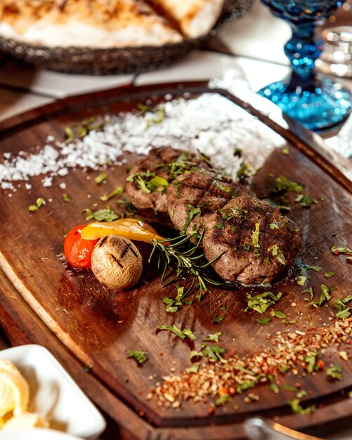 Carne frita servida com batata assada, tomate, folhas de alecrim e fatia de pimentão