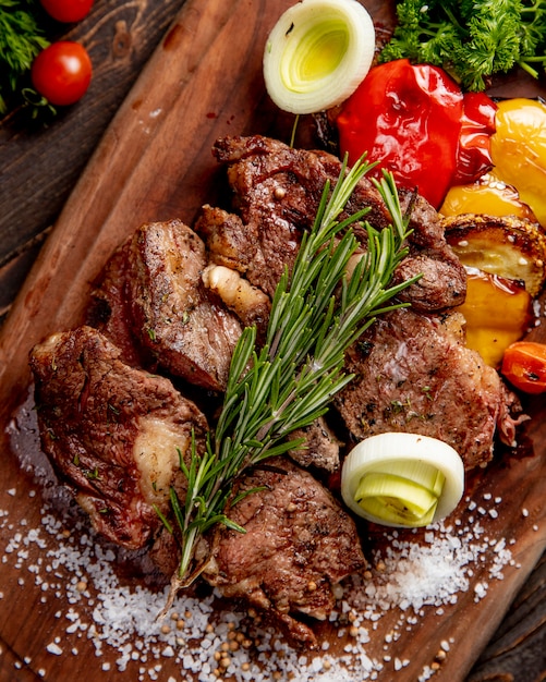 Foto grátis carne frita servida com legumes grelhados, cebola e raminho de alecrim