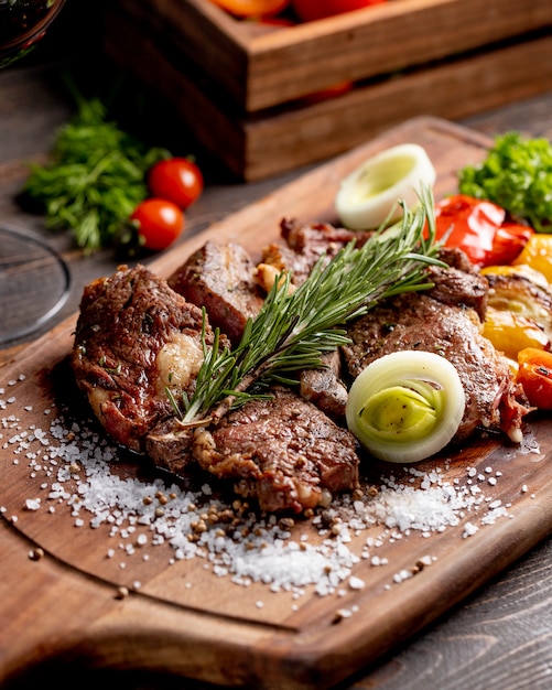 Carne frita servida com legumes grelhados, cebola e raminho de alecrim