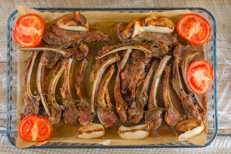 Foto grátis carne grelhada com tomate, maçã em uma assadeira de vidro na mesa de madeira, plana leigos.