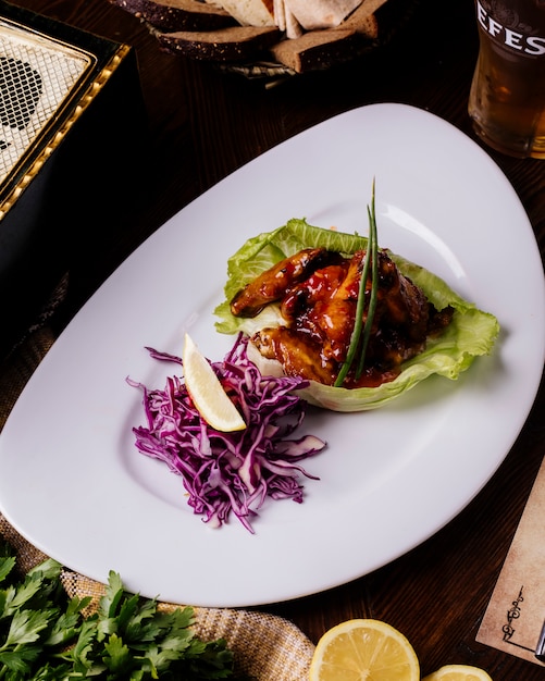 Carne grelhada em molho teriyaki em folha de alface com salada de repolho roxo e limão.