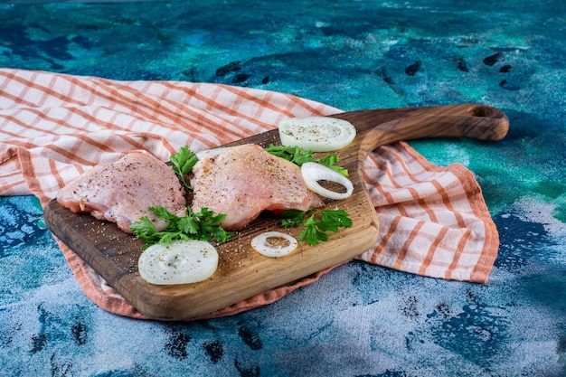 Foto grátis carnes de frango em uma tábua de corte sobre o pano de prato