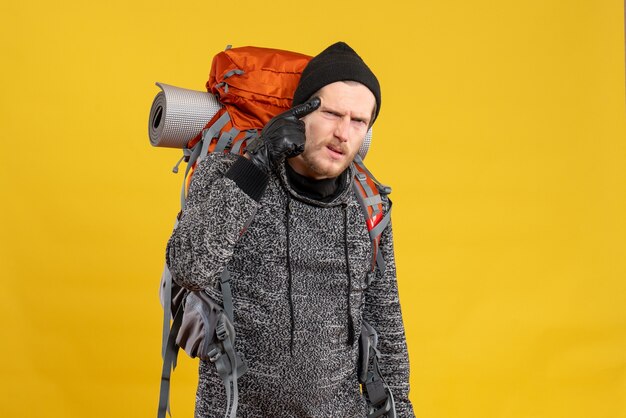 carona masculino com luvas de couro e mochila colocando o dedo na têmpora