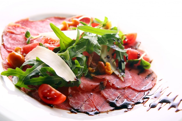 Carpaccio de carne de bovino servido com rúcula