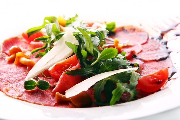 Carpaccio de carne de bovino servido com rúcula