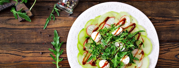 Carpaccio de rabanete com rúcula, mussarela e molho balsâmico. Comida saudável. Salada Daikon. Postura plana. Vista do topo